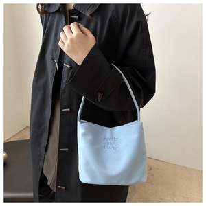 Detail of light blue fabric handbag with pretty and liberty embroidery on black coat