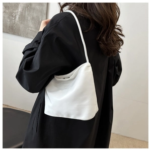 Close-up of a white shoulder bag with engraved lettering and slim shoulder strap