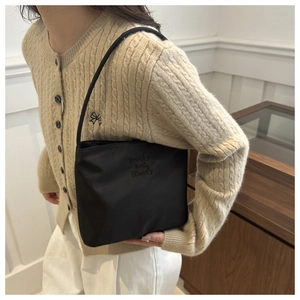 Gros plan du sac à bandoulière noir minimaliste avec texte brodé sur tissu haut de gamme