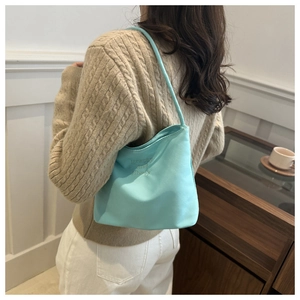 Light blue hobo bag with 'pretty and liberty' embroidery shown on model shoulder