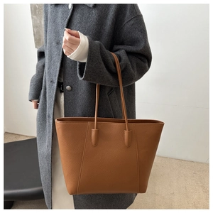Detail of brown litchi grain leather texture on minimalist large capacity tote bag