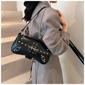 Punk style black rivet shoulder bag with silver buckle worn with a gray blazer
