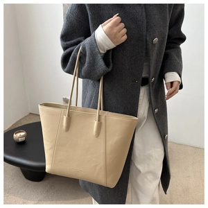 Detail of light khaki tote bag showing fine pebble grain texture and shoulder strap