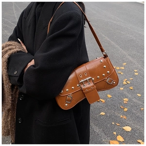 Detail of vintage caramel brown rivet shoulder bag with metallic buckle and stud accents