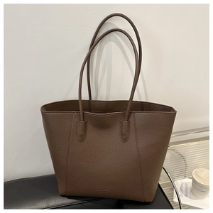 Detail of coffee brown tote bag showing lychee grain leather texture and embossed logo