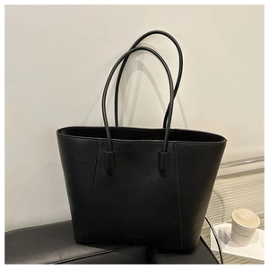 Detail of black lychee grain leather tote bag with elegant embossed logo and long straps