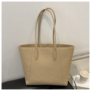 Detailed close-up of beige faux leather tote bag texture with minimalist logo embossing