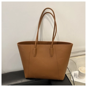 Detailed macro view of caramel brown lychee texture leather on a large tote bag