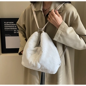 Detail of white plush tote bag with slim faux leather strap and silver metal chain link