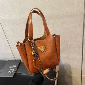 Gros plan d'un sac cabas vintage en cuir marron avec logo en métal et breloque tissée main