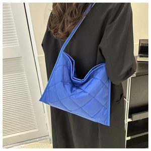 Quilted blue tote bag shown on a model side view highlighting the shoulder strap