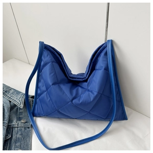 Detail der blauen gesteppten Puffer-Tasche mit Rautenmuster und schmalem Schultergurt