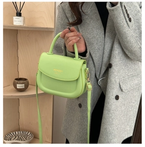 Close-up of lime green leather saddle bag with gold hardware and fashion lettering