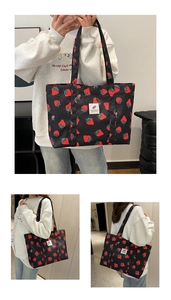 Detail view of large capacity black tote bag with red strawberry print and handles