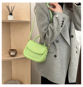 Close-up of lime green saddle bag in textured PU leather with golden fashion lettering