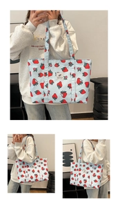 Detail of light blue tote bag featuring strawberry print and logo patch on canvas