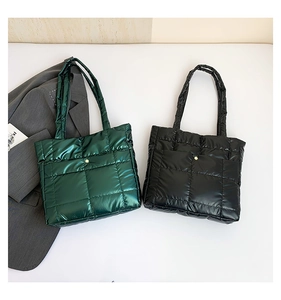 Detail of quilted puffer tote bags in green and black with metal buckle and soft texture
