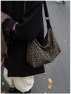 Detail of leopard print canvas bucket bag with wide strap and zipper on street