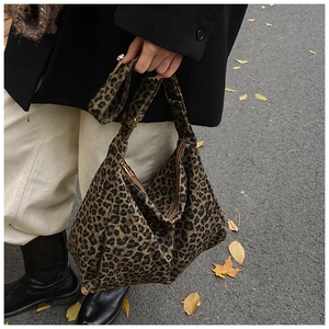 Street style view of leopard print bucket bag paired with a black blazer and white pants