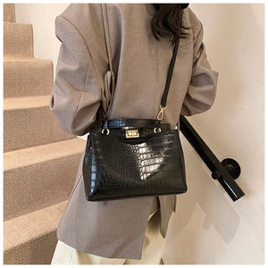 Close-up of black crocodile pattern faux leather handbag with golden twist lock detail