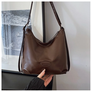Detail of dark brown faux leather tote showing the logo and dual strap texture