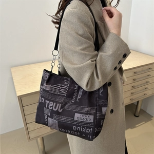 Elegante borsa tote con stampa a giornale e catena d'argento indossata da una modella chic