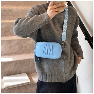 Detail of sky blue crossbody camera bag with 3D SM logo and geometric jacquard strap