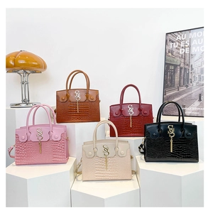 Détail de sacs à main en cuir crocodile multicolores avec pendentifs dorés en forme de S