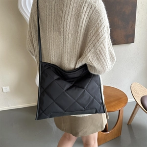 Minimalist black quilted tote bag with diamond lattice pattern for women on model