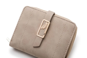 Close-up of matte apricot leather wallet with golden leaf buckle and logo zipper
