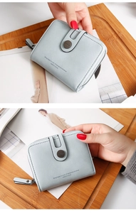 Close-up of a light blue PU leather short wallet with a U-shaped zipper and snap button