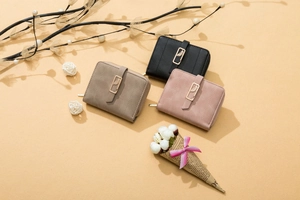 Three matte leaf buckled short zip wallets in black, khaki and pink shown with dried flowers