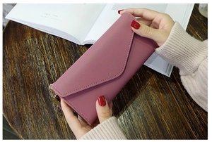Detail of dusty pink long envelope wallet in PU leather with gold zipper and heart tassel