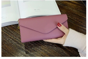 Close-up of pink long envelope wallet with heart charm and decorative stitching detail