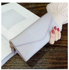 Detailed close-up of light gray long envelope wallet with tassel and golden chain