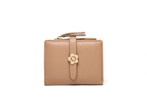 Detail of light pink leather wallet featuring floral gold clasp and lychee texture