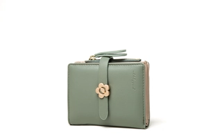 Detail of green bifold wallet showing pebbled leather texture and flower metal clasp
