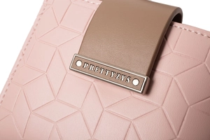 Close-up of pink PU leather wallet with geometric embossing and engraved metal buckle