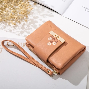 Detail of tan PU leather wallet with daisy print, gold buckle, and metal zipper closure