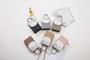 Flat lay of multiple floral print touchscreen phone bags in six elegant pastel colors