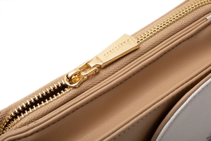 Macro detail of golden metal zipper and high-quality stitching on a beige leather phone bag