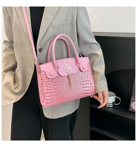 Détail du sac rose embossé crocodile avec breloque dorée S et pompons à franges