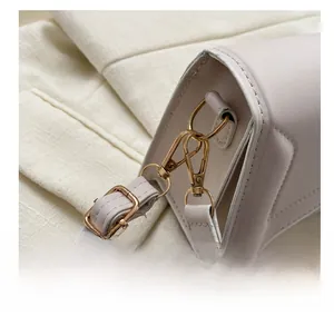 Detailed close-up of premium gold-toned metal hooks and hardware on a beige shoulder bag