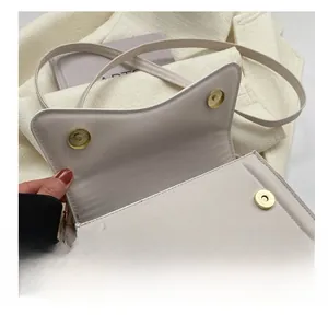 Detail view of the cream white crossbody bag showing dual magnetic snap closures in gold
