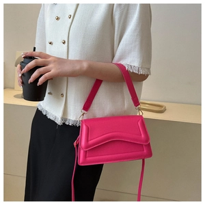 Detailed view of magenta rectangular crossbody bag with wave geometric quilting and PU leather