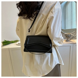 Detailed side view of a black minimalist crossbody bag with textured leather surface