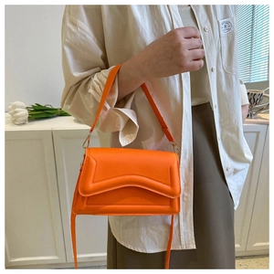 Detail of bright orange cross-body bag with modern V-shaped quilted texture on the flap