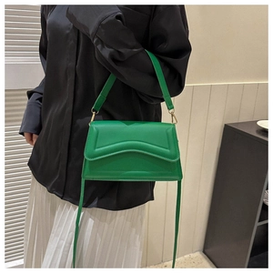Detail of green leather crossbody bag with V-shaped stitching and gold metal hardware