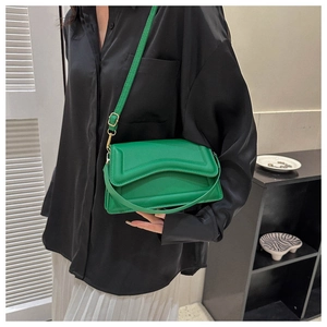 Detail of vibrant green crossbody bag with wave quilted texture and gold hardware on person
