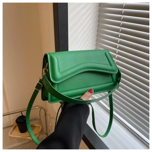 Detail of bright green crossbody bag featuring wavy edge stitching and gold metal buckle